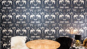 A room with a patterned wallpaper featuring animal prints, a round wooden table, and two chairs with fur upholstery. - The Brunstane Studio  (Edinburgh, Scotland)