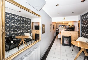 A modern living room with a fireplace, a dining area, and a kitchen in the background. - The Brunstane Studio  (Edinburgh, Scotland)