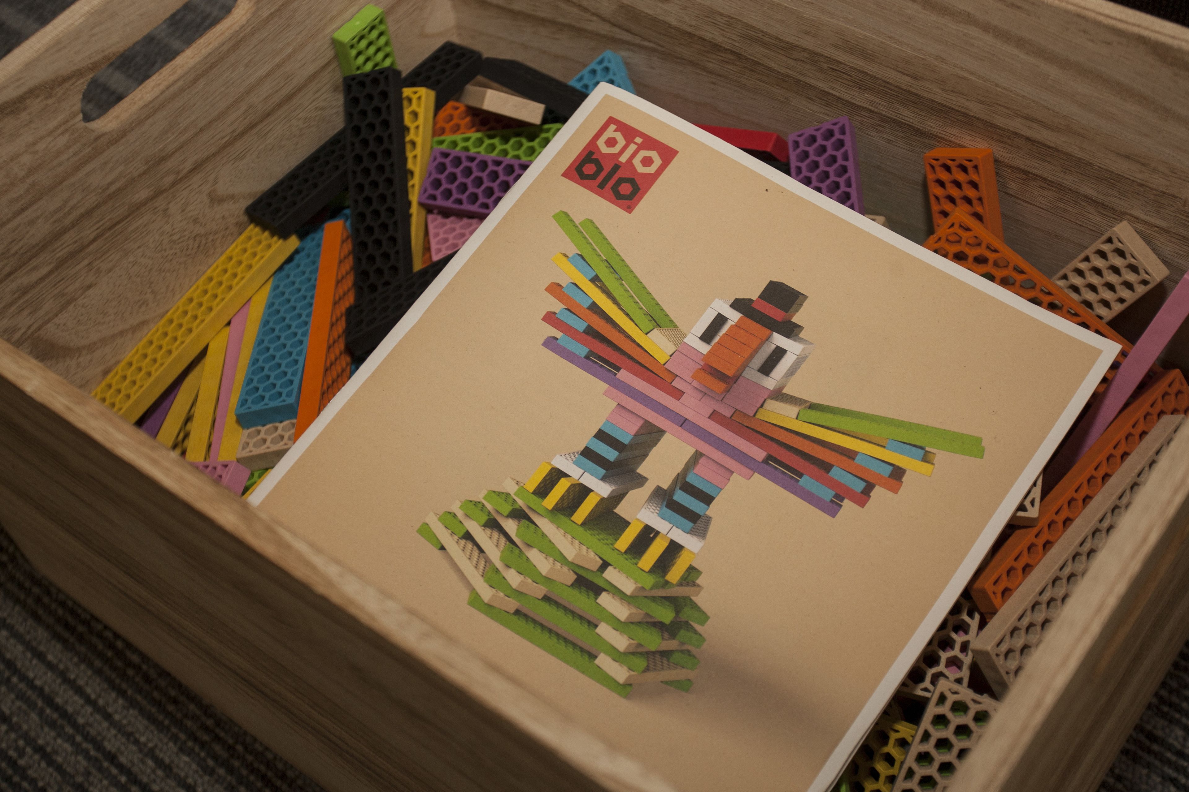 A wooden crate filled with colorful building blocks and a card with 'bio bio' text.
