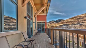 A wooden deck with chairs, a glass door, and a view of a hilly landscape. - Large 4 Bedroom Ski-in/Out, Sleeps 12, Vaulted Ceilings, Pool, Hot Tub MC12B (Park City)