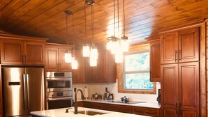 A kitchen with wooden cabinets, stainless steel appliances, and pendant lighting. - Christine's Paradise! (Sevierville)