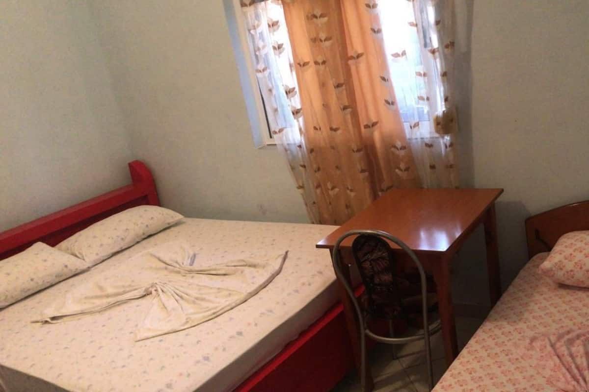 Una habitación con dos camas, una mesa y una silla.