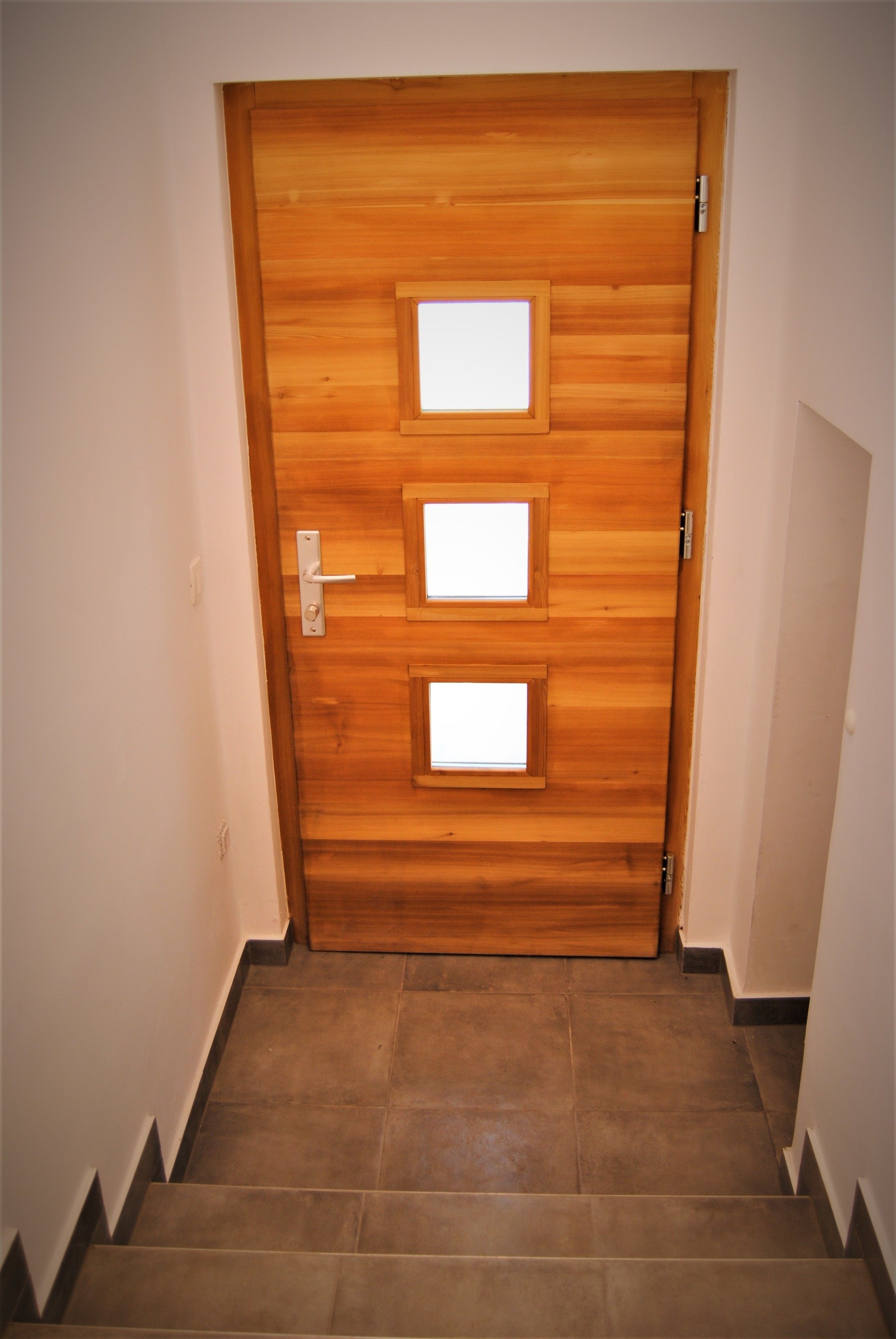 A wooden door with three rectangular windows and a door handle.