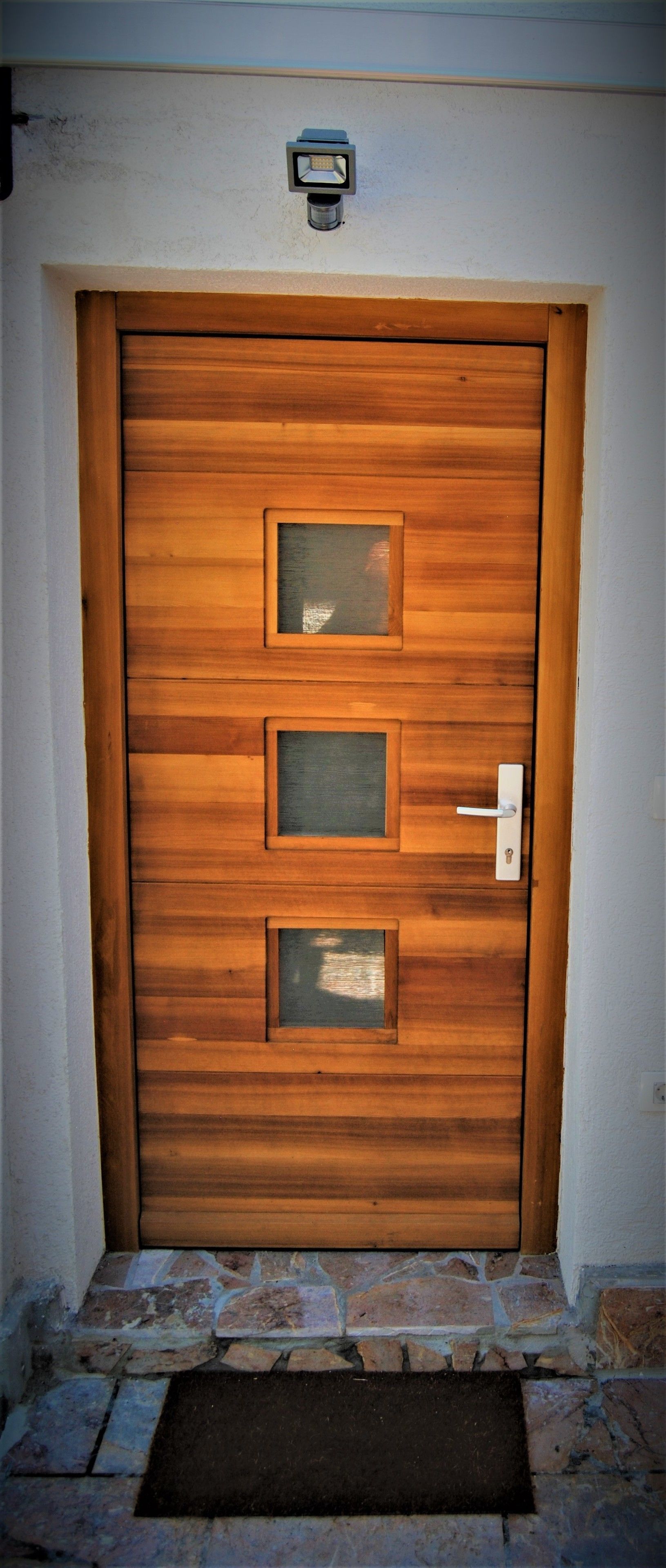 A wooden door with three glass panels and a keyhole.