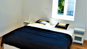 A bedroom with a large window, a bed with a black bedspread, white nightstands, and a white wall. - Rose Valley Ljubljana (Ljubljana)