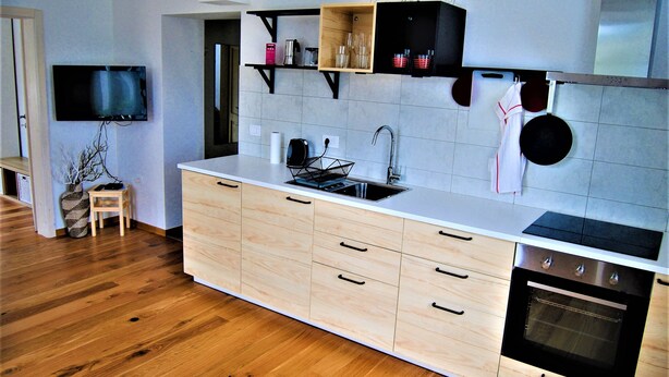 A modern kitchen with wooden cabinets, a built-in oven, and a large island with a sink. - Rose Valley Ljubljana (Ljubljana)