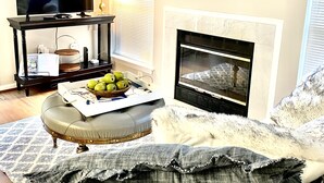 A living room with a television, a fireplace, a clock, and a sofa with cushions. - Your Annapolis Adventure Starts Here!!  (Annapolis)