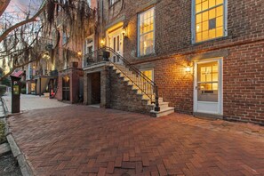 A brick building with a staircase leading to a second floor, a mailbox, and a door with a window.
