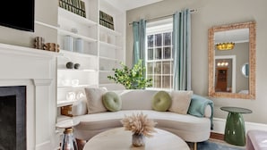 Ein Wohnzimmer mit einem weißen Sofa, einem runden Couchtisch, einem Kamin und einem Bücherregal.