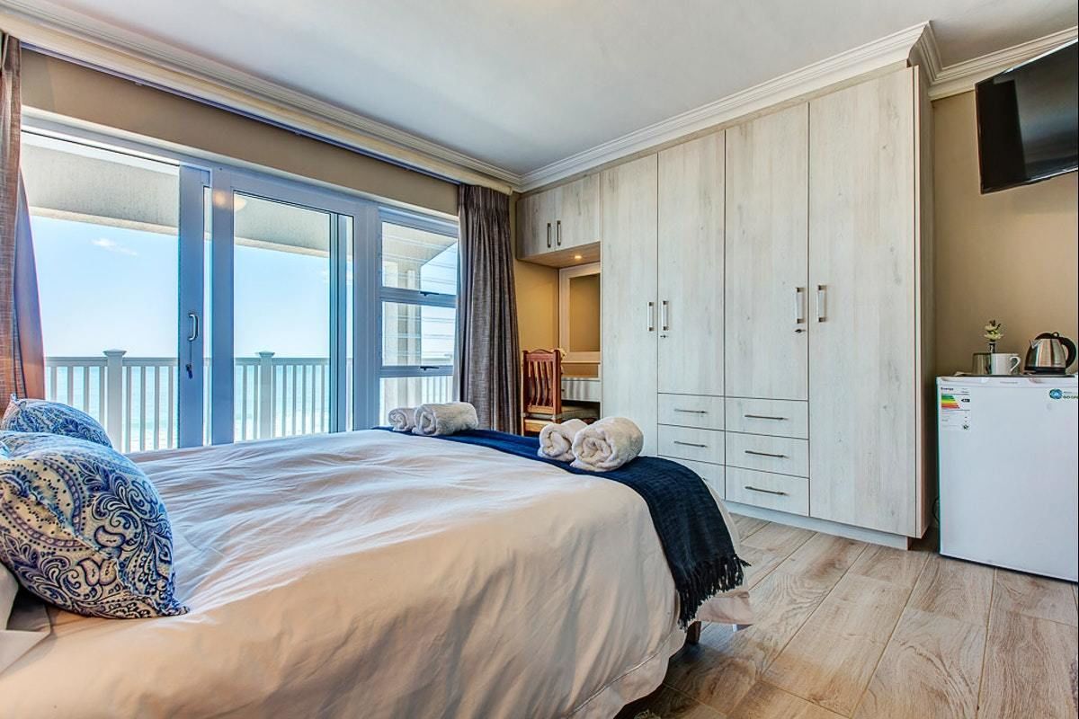 Una habitación de hotel con una cama grande, un armario, televisión y un balcón con vistas.