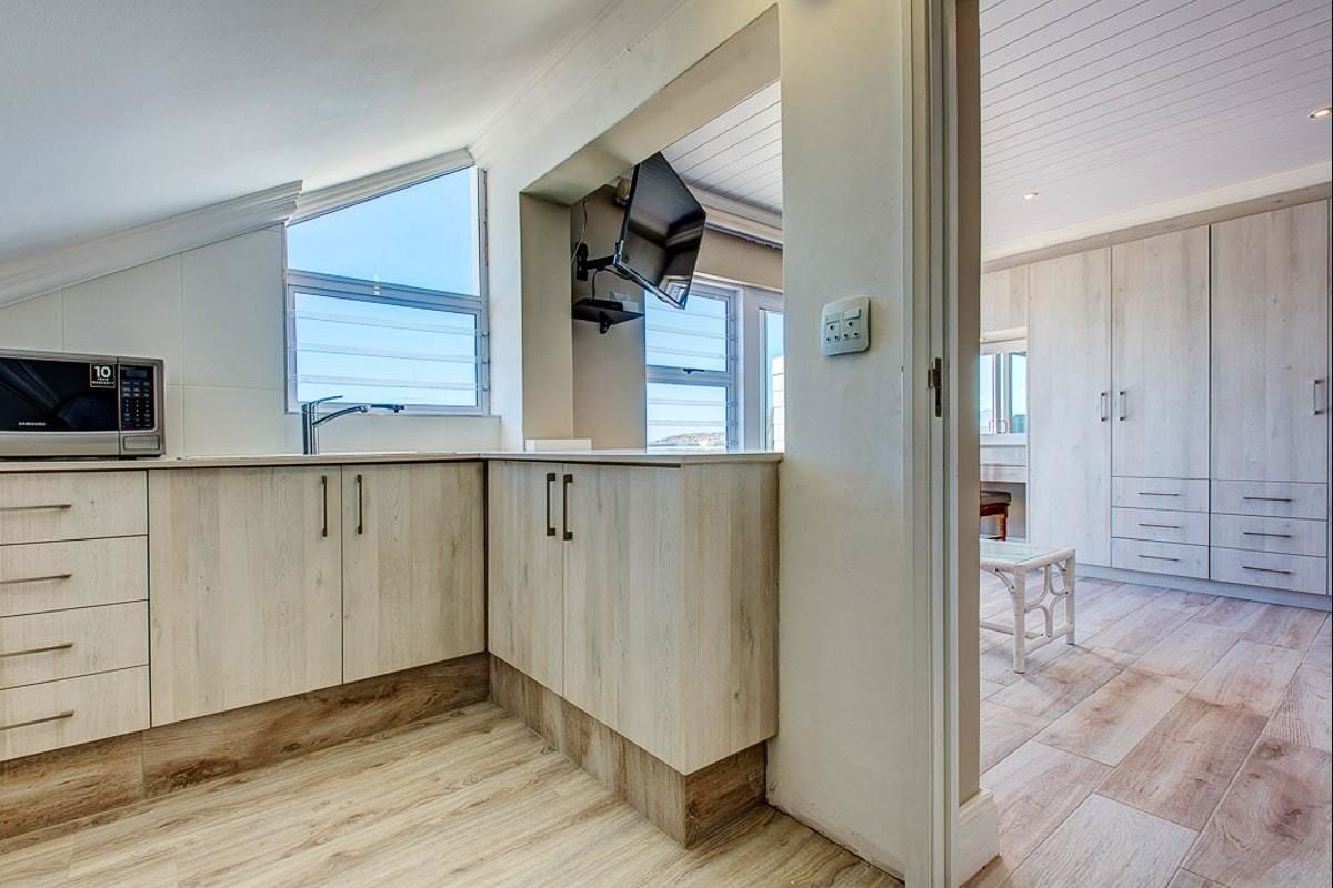 Une cuisine moderne avec des meubles de couleur bois clair, un four à micro-ondes et une grande fenêtre.