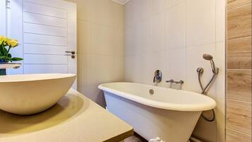 A bathroom with a freestanding bathtub, a sink with a bowl, and a shower area.
