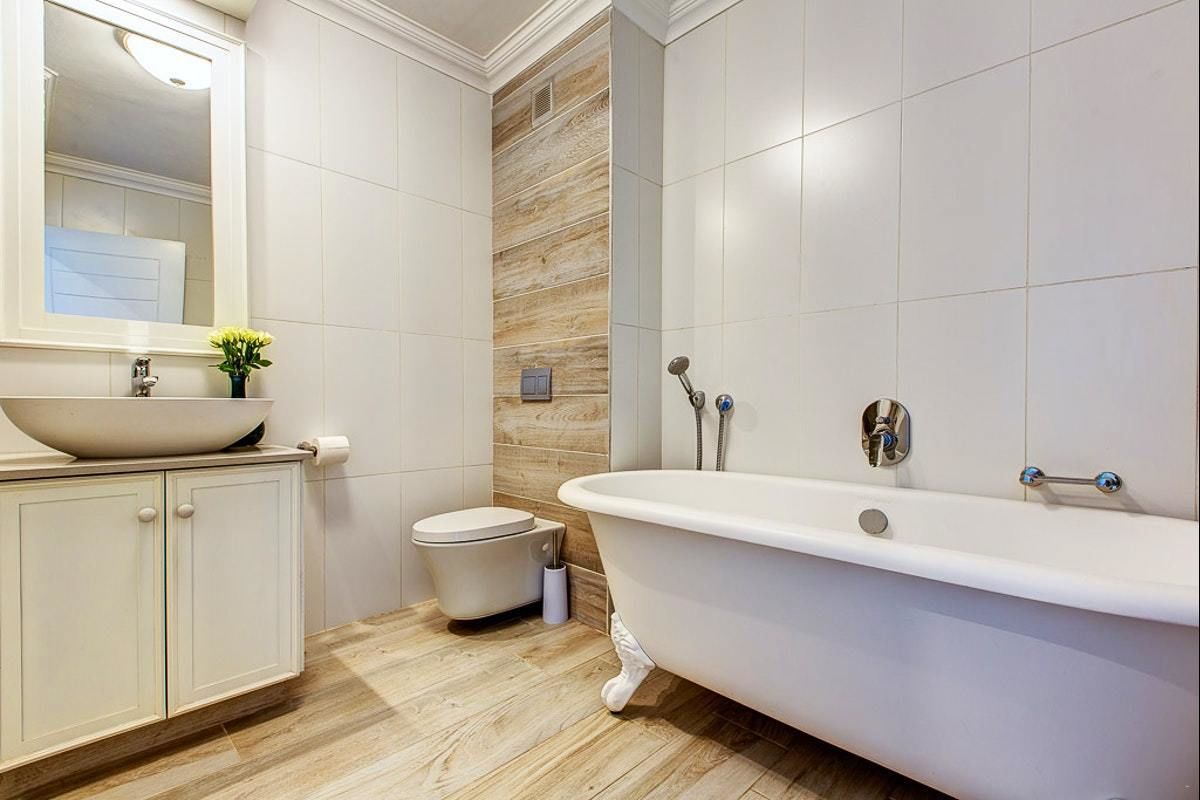 A bathroom with a freestanding bathtub, a sink with a mirror, and a toilet.