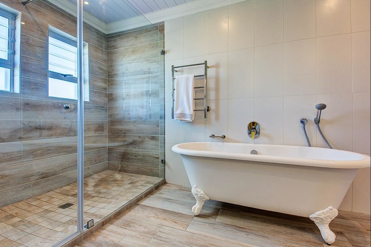 A modern bathroom with a freestanding bathtub, a glass shower enclosure, and a towel rack.