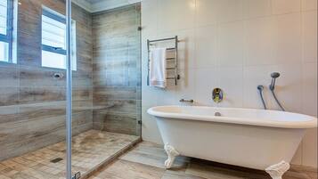 A modern bathroom with a freestanding bathtub, a glass shower enclosure, and a towel rack.