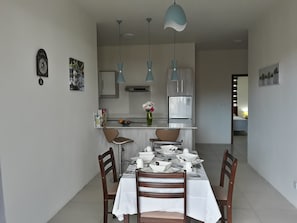 Enjoy meals in this stylish dining area with a central table for four, kitchenette, and modern appliances.