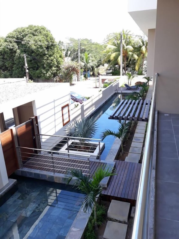 Relax by the pool surrounded by lush greenery and lounge chairs.