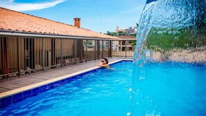 A swimming pool with a tiled deck and a person swimming. - Gabvini Hotel (Lima Duarte)