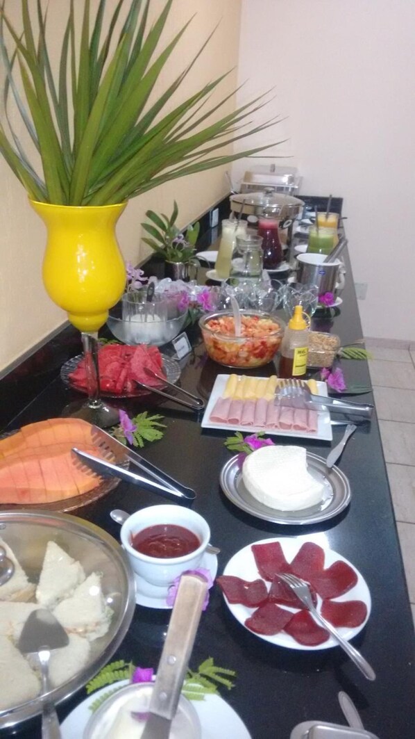 Une table de buffet proposant divers plats, notamment des viandes et fromages en tranches, ainsi qu’un gâteau.