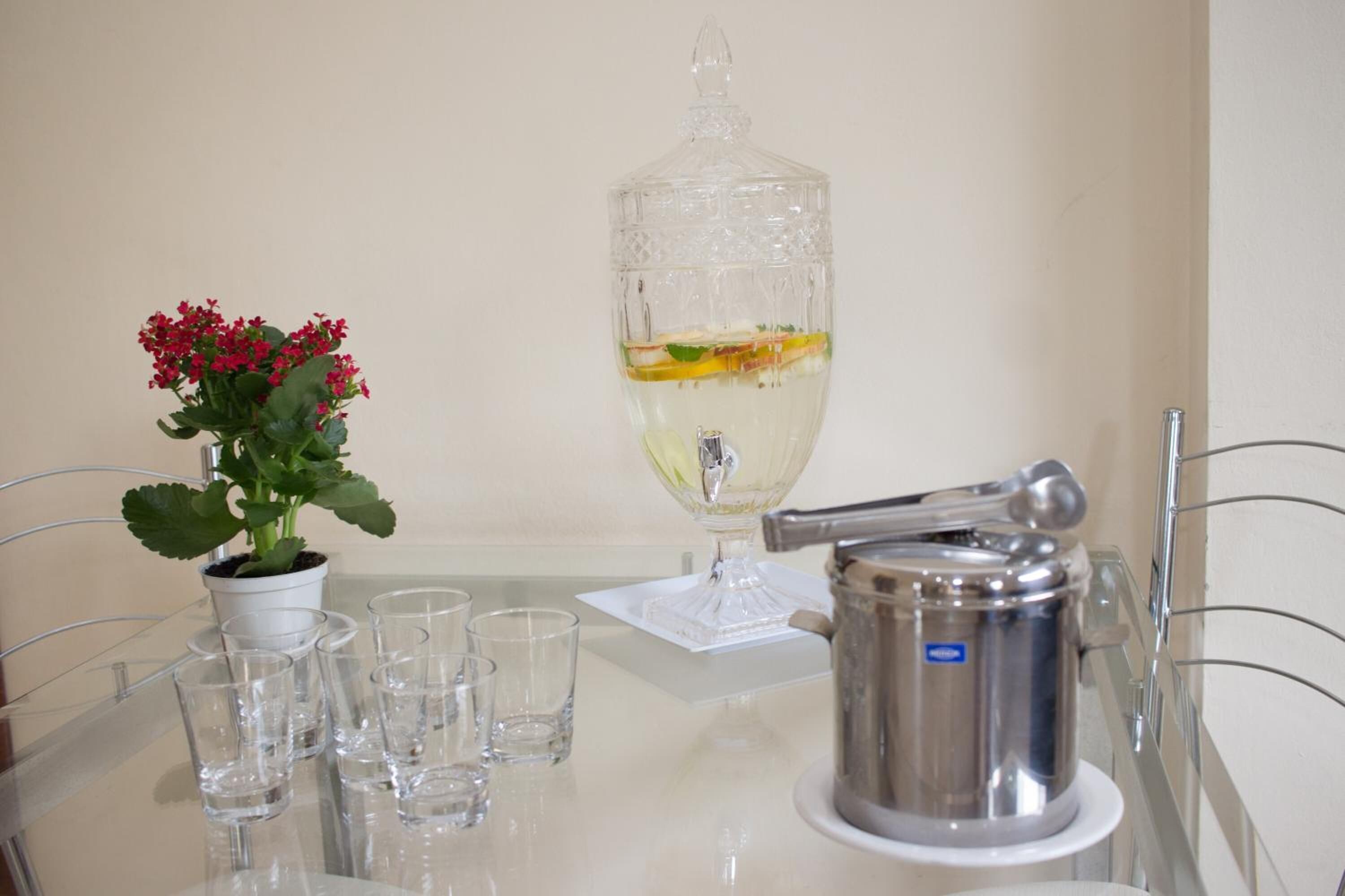 Ein Tisch mit einem Blumentopf, einem Glas Weißwein und einer silbernen Teekanne.