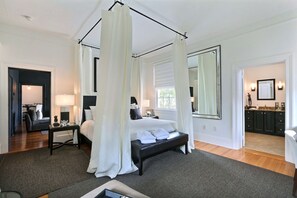 Une chambre à coucher avec un lit à baldaquin, un grand miroir et une vue sur la salle de bain.