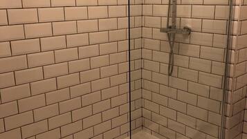 A glass-enclosed shower with white subway tiles on the walls and floor.