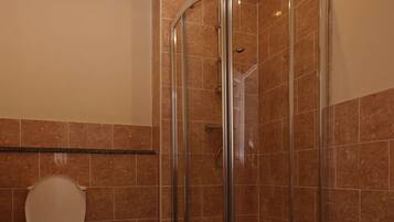 Un baño con ducha de mampara de vidrio, inodoro y lavabo.