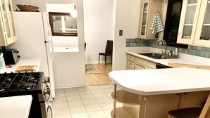 A compact kitchen with a gas stove, white cabinets, a small window, and a tiled floor.
