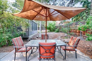 A patio with a table and chairs, an umbrella, and a wooden fence. - Skyline Stargazing Cabin with hot tub (Flagstaff)