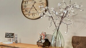 A wooden desk with a clock, a vase with branches, and a sign for a guest book. - Heated Pool Access | 5*Clean | Flex Cancelation (Savannah)