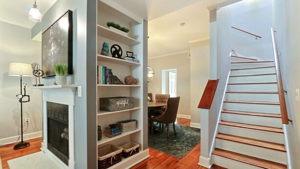 A modern living room with a fireplace, a bookshelf, and a staircase. - Heated Pool Access | 5*Clean | Flex Cancelation (Savannah)
