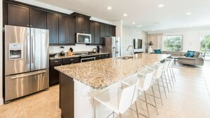 A modern kitchen with dark cabinets, stainless steel appliances, and a granite countertop.