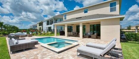A modern two-story house with a swimming pool, outdoor seating, and a well-maintained lawn.
