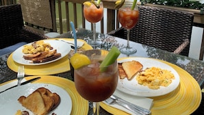 A dining table with breakfast plates, toast, scrambled eggs, and Bloody Mary cocktails.