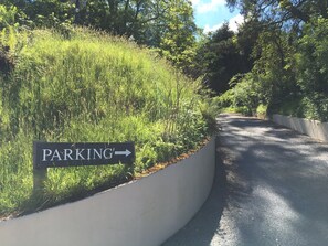 Find your way to parking via this convenient sign, nestled among lush greenery and trees.