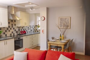 A modern kitchen with a toaster, oven, and a dining area with a table set for two.