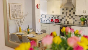 A modern kitchen with white cabinets, a checkered backsplash, and a red kettle on the counter. - Corffe Cottages, Perfect Devon retreat, sleeps 4, heated indoor pool (Barnstaple)
