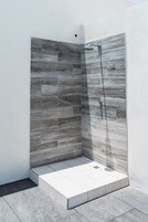 Un área de ducha moderna con diseño de azulejos grises y blancos.