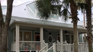 A two-story house with a covered porch, white railings, and a small garden area. - Steinhatchee Landing Resort-# 5 Nautical Cottage-Boat slip-Newly remodeled (Steinhatchee)