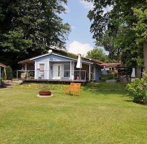 A single-story house with a porch, a small garden, and a bench. - Cottage with terrace directly on the Krüpelsee (Zernsdorf)