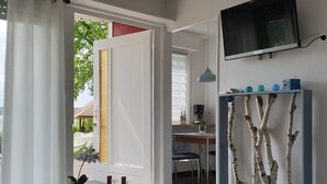 Ein modernes Wohnzimmer mit Esstisch, Wand-Fernseher und dekorativer Regalvorrichtung aus einem Zweig.