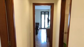 Un couloir au plancher de bois menant à une pièce dotée d’une porte.