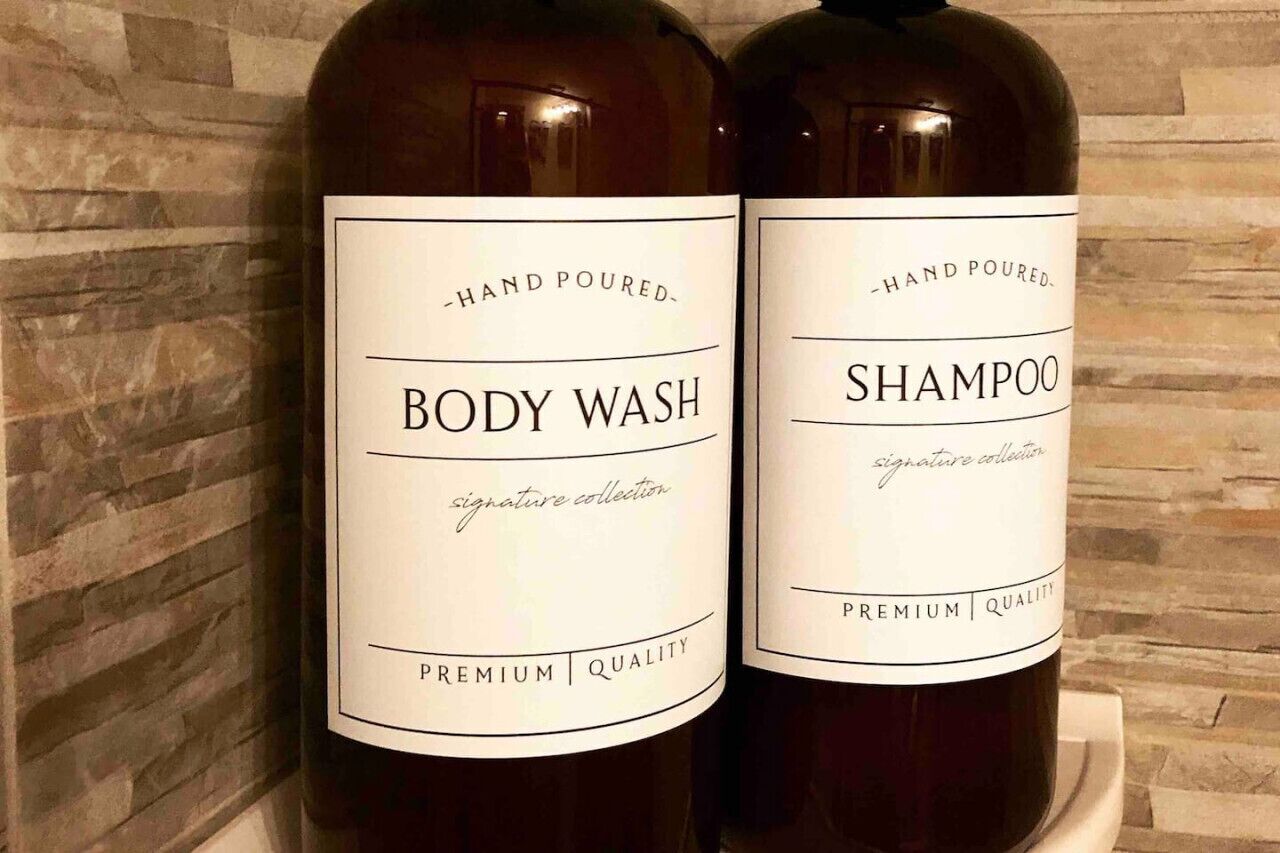 Two bottles of hand-poured body wash and shampoo with labels indicating they are part of a signature collection and premium quality.