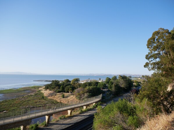 A coastal landscape with a bridge, railway tracks, and a clear view of the sea and distant mountains. - Beautiful Home with Spectacular Bay View From Patio! (Pinole)