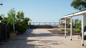 Eine geräumige Terrasse mit Meerblick, einer überdachten Sitzgelegenheit und Kübelpflanzen.