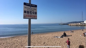 Une scène de plage avec un panneau indiquant « Ville de Fréjus » et « Bienvenue sur la plage du Capitole ».