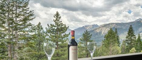 Une bouteille de vin et deux verres sur une table, avec une vue sur la montagne.