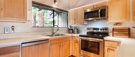 A modern kitchen with wooden cabinets, stainless steel appliances, and a window providing natural light.