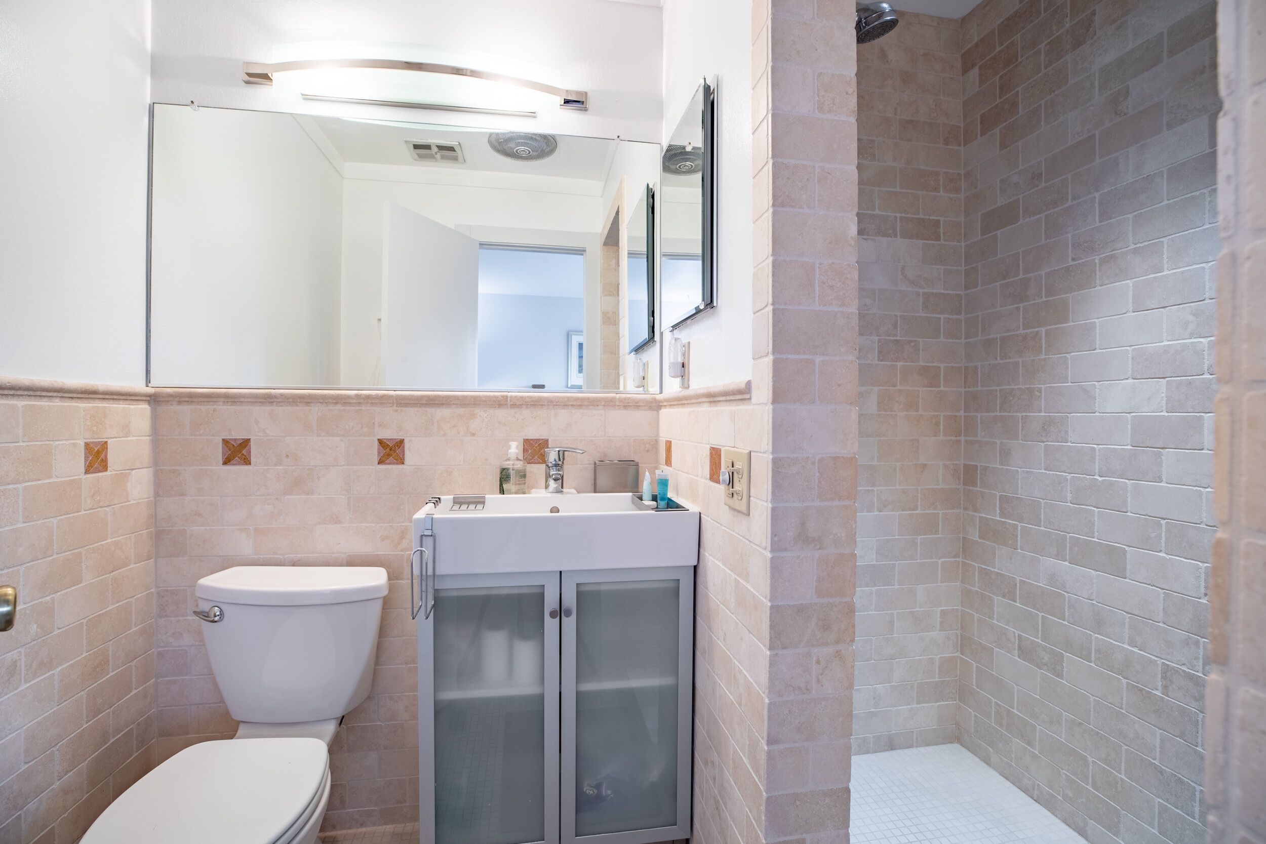 A bathroom with a toilet, sink, and shower area.