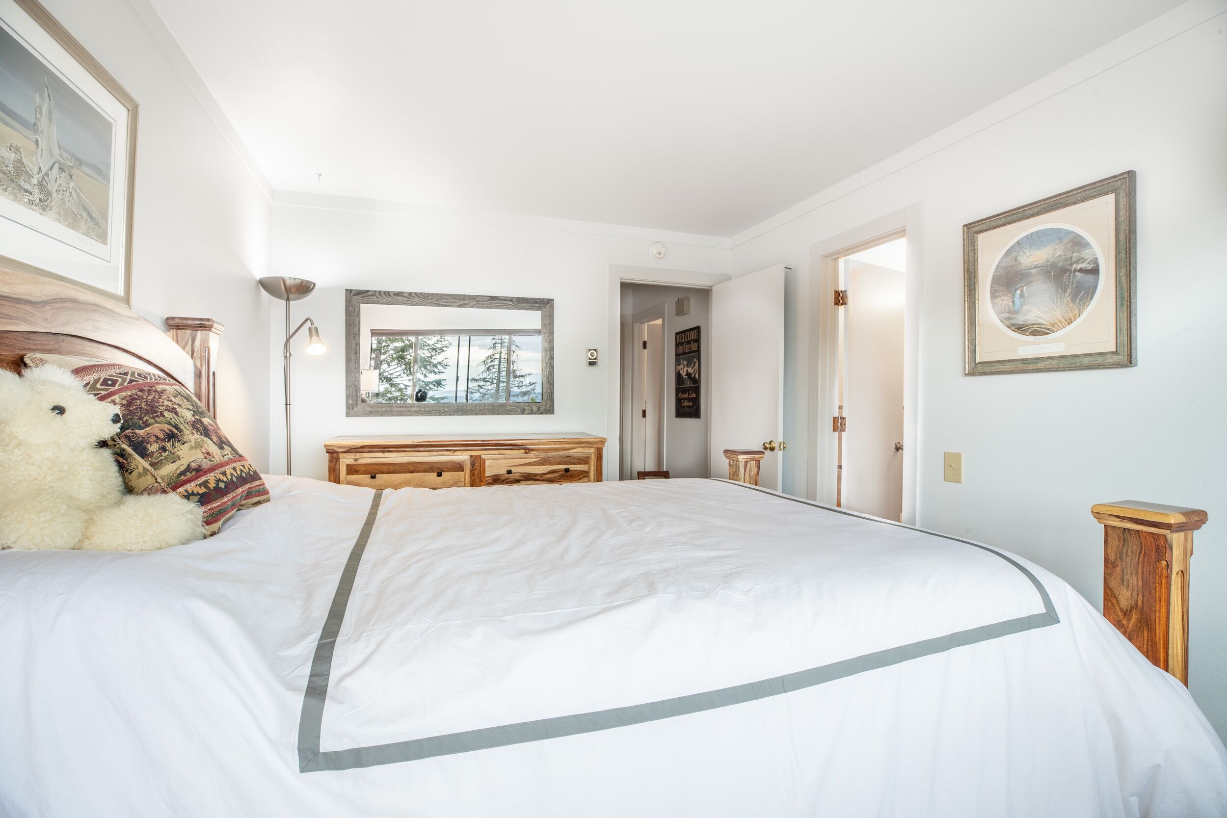 Un dormitorio con una cama grande, un aparador de madera y un espejo en la pared.